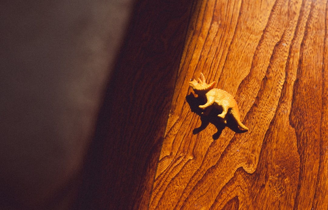 Tiny dinosaur toy on a wooden surface