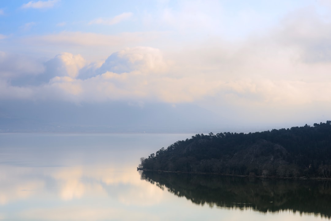Calm lake reflecting cloudy sky and forested shore