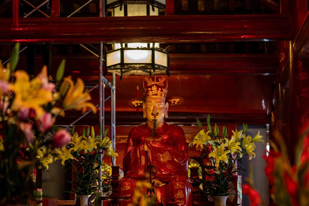 Ornate statue adorned with flowers in a temple.